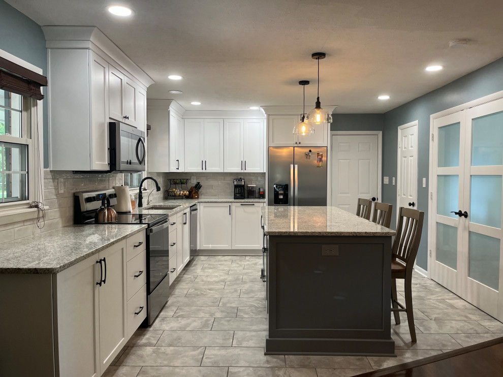 Inspiration for a mid-sized country l-shaped eat-in kitchen in Indianapolis with an undermount sink, shaker cabinets, white cabinets, granite benchtops, grey splashback, porcelain splashback, stainless steel appliances, porcelain floors, with island, grey floor and grey benchtop.