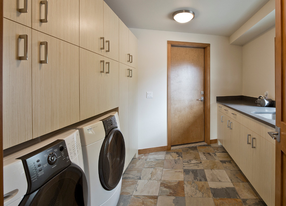 Mid-sized contemporary galley utility room in Seattle with an undermount sink, flat-panel cabinets, light wood cabinets, quartz benchtops, white walls, slate floors and a side-by-side washer and dryer.
