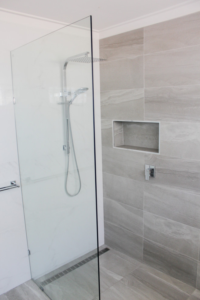 Photo of a large modern 3/4 wet room bathroom in Perth with flat-panel cabinets, white cabinets, a freestanding tub, white tile, ceramic tile, white walls, porcelain floors, an integrated sink, solid surface benchtops, grey floor, an open shower and white benchtops.