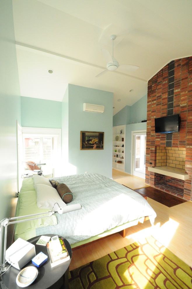 Inspiration for a mid-sized contemporary master bedroom in DC Metro with blue walls, light hardwood floors, a brick fireplace surround, a standard fireplace and beige floor.
