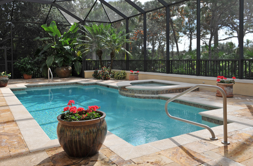 This is an example of a mediterranean backyard rectangular pool in Miami with a hot tub and natural stone pavers.