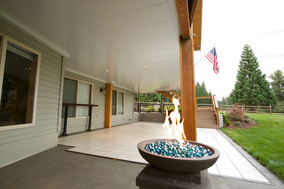 Large mountain style backyard outdoor kitchen deck photo in Seattle with a roof extension