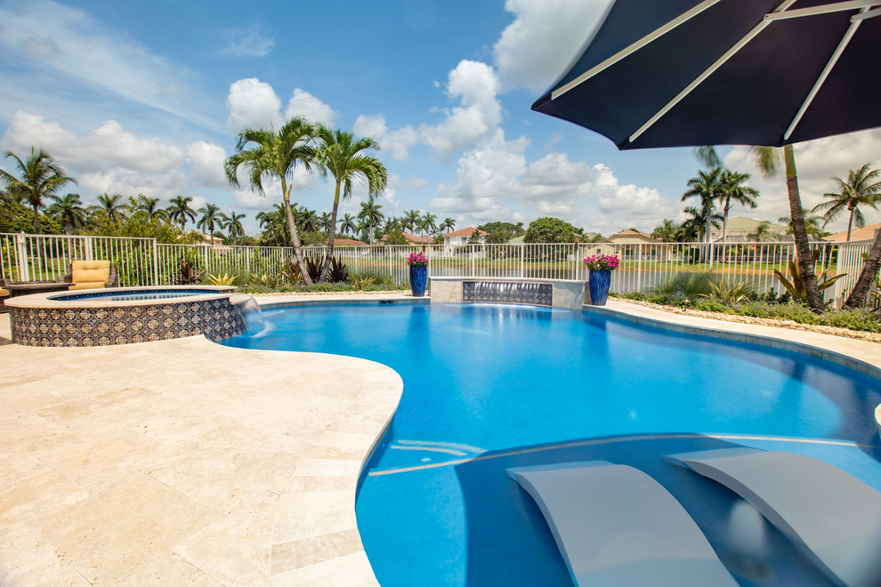 Mid-sized modern backyard custom-shaped natural pool in Miami with natural stone pavers.