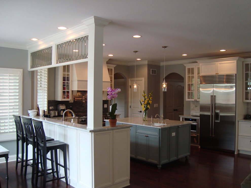 This is an example of a large traditional l-shaped open plan kitchen in Chicago with a double-bowl sink, white cabinets, granite benchtops, stainless steel appliances, dark hardwood floors, with island, recessed-panel cabinets, grey splashback and stone tile splashback.