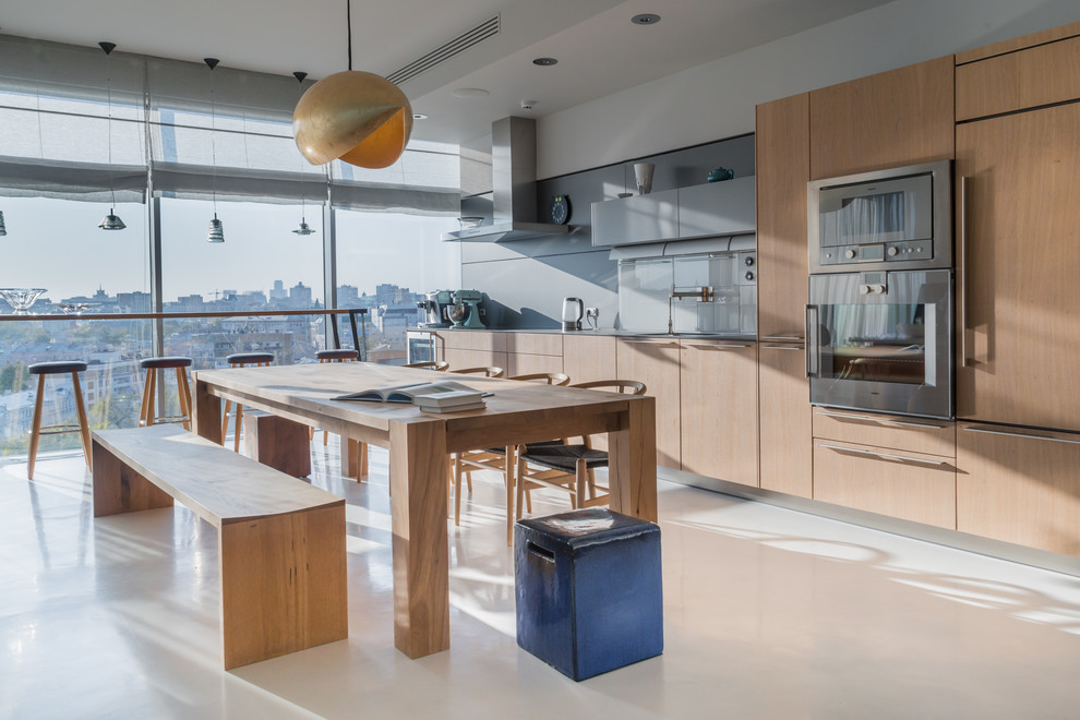 This is an example of a contemporary open plan kitchen in Moscow with flat-panel cabinets, light wood cabinets, grey splashback, no island and stainless steel appliances.