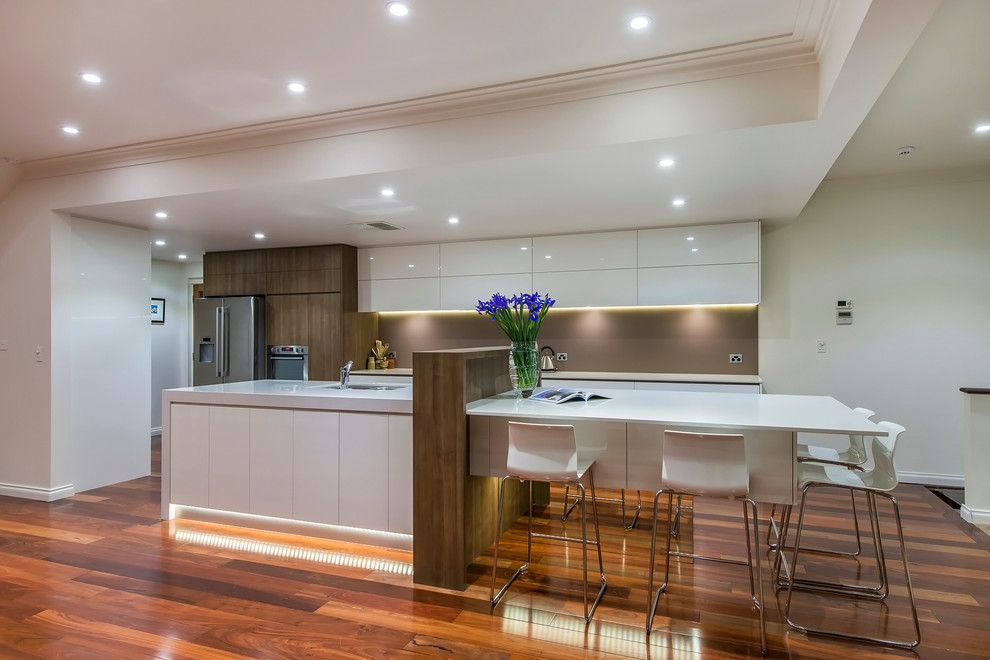 Photo of a large contemporary galley eat-in kitchen in Perth with an undermount sink, flat-panel cabinets, white cabinets, quartz benchtops, brown splashback, porcelain splashback, stainless steel appliances, dark hardwood floors and with island.