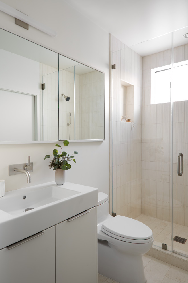 This is an example of an industrial bathroom in San Francisco with flat-panel cabinets, white cabinets, an alcove shower, a one-piece toilet, white tile, white walls, a console sink, beige floor, a hinged shower door, a niche and a single vanity.