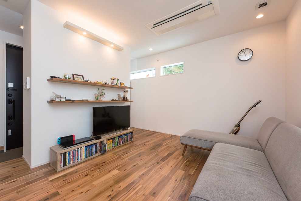 Photo of a mid-sized industrial formal open concept living room in Tokyo Suburbs with white walls, medium hardwood floors, a freestanding tv and brown floor.