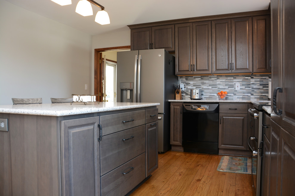 Mid-sized transitional l-shaped separate kitchen in DC Metro with an undermount sink, raised-panel cabinets, grey cabinets, quartz benchtops, multi-coloured splashback, mosaic tile splashback, stainless steel appliances, light hardwood floors, with island, brown floor and white benchtop.