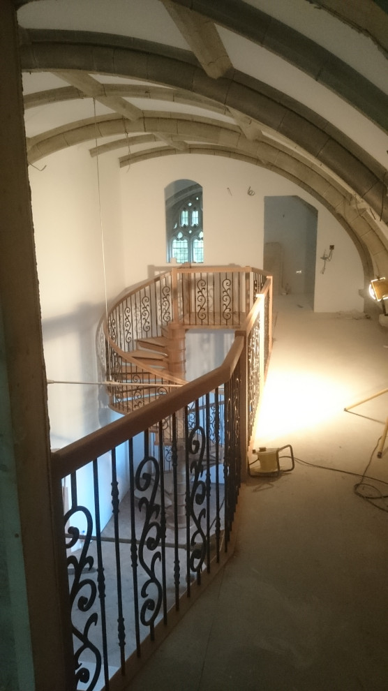 На фото: большая винтовая деревянная лестница в викторианском стиле с деревянными ступенями и металлическими перилами с
