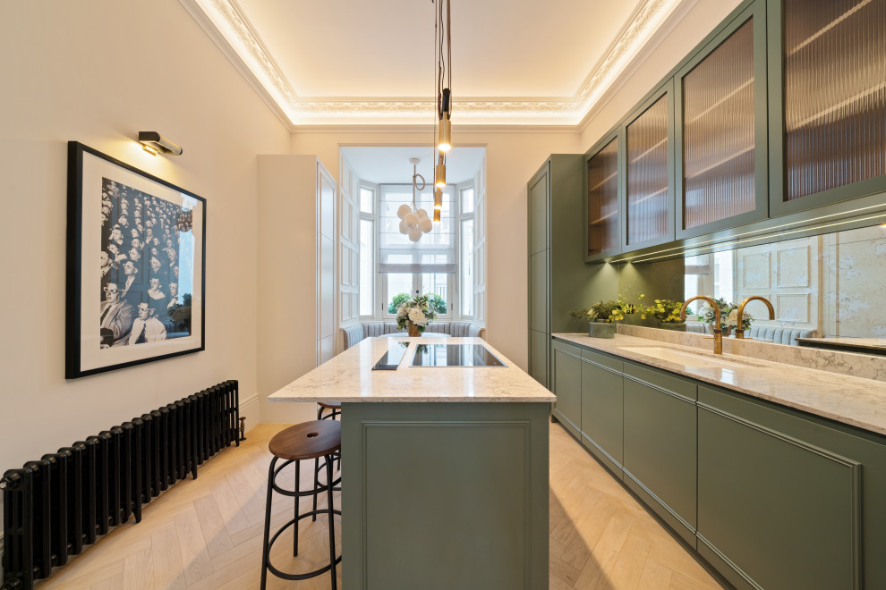 ロンドンにある高級な中くらいなトランジショナルスタイルのおしゃれなキッチン (シングルシンク、レイズドパネル扉のキャビネット、緑のキャビネット、クオーツストーンカウンター、メタリックのキッチンパネル、ミラータイルのキッチンパネル、パネルと同色の調理設備、淡色無垢フローリング、ベージュの床、ベージュのキッチンカウンター) の写真