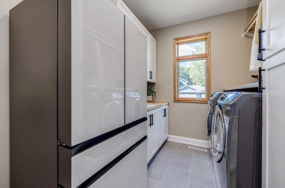 This is an example of a large classic u-shaped utility room in Minneapolis with a built-in sink, shaker cabinets, white cabinets, wood worktops, beige walls, ceramic flooring, a side by side washer and dryer, grey floors and brown worktops.