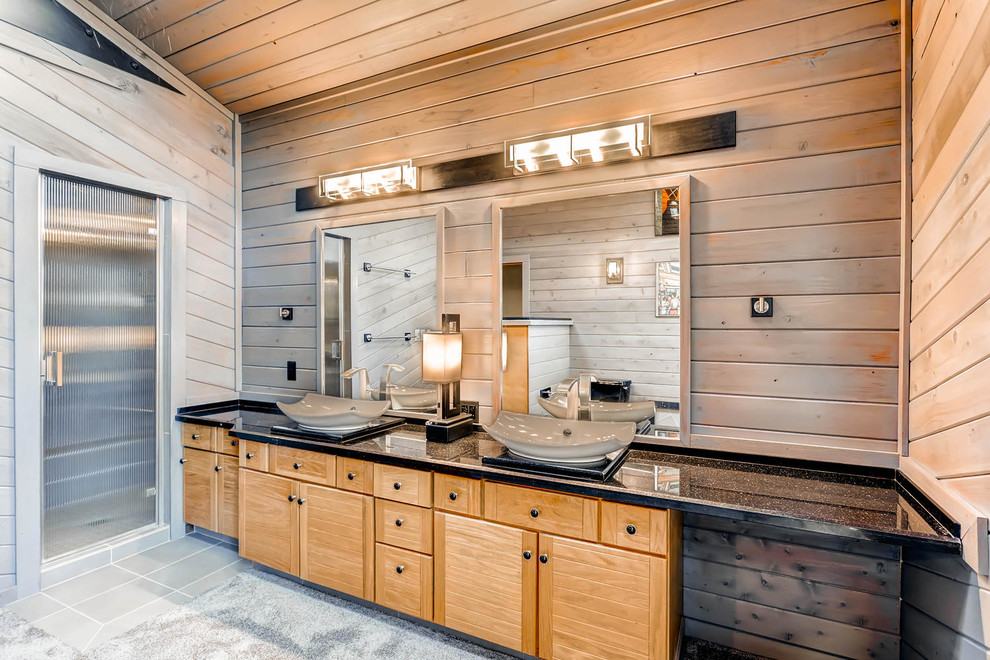 Mid-sized mountain style master black tile concrete floor bathroom photo in Denver with flat-panel cabinets, light wood cabinets, a one-piece toilet, brown walls, a vessel sink and quartzite countertops
