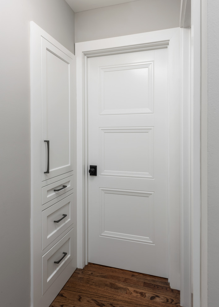 Aménagement d'une petite armoire encastrée classique neutre avec un placard avec porte à panneau encastré, des portes de placard blanches, un sol en bois brun et un sol marron.