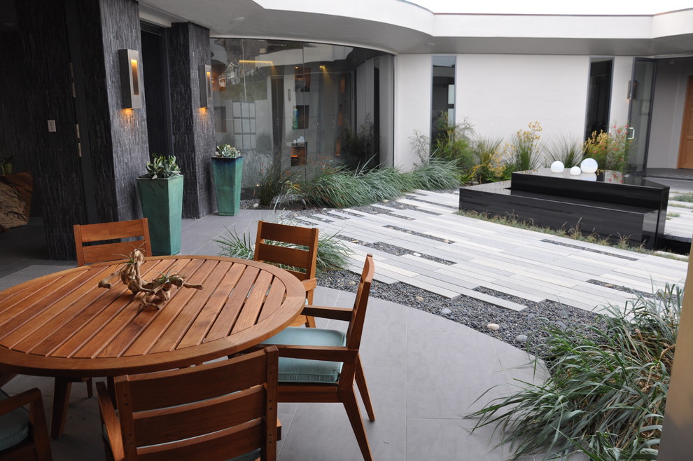 This is an example of a contemporary courtyard garden in San Luis Obispo with a water feature.