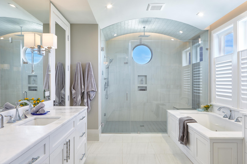 Beach style master bathroom in Other with shaker cabinets, white cabinets, a drop-in tub, an alcove shower, white tile, beige walls, an undermount sink, white floor, a hinged shower door and white benchtops.