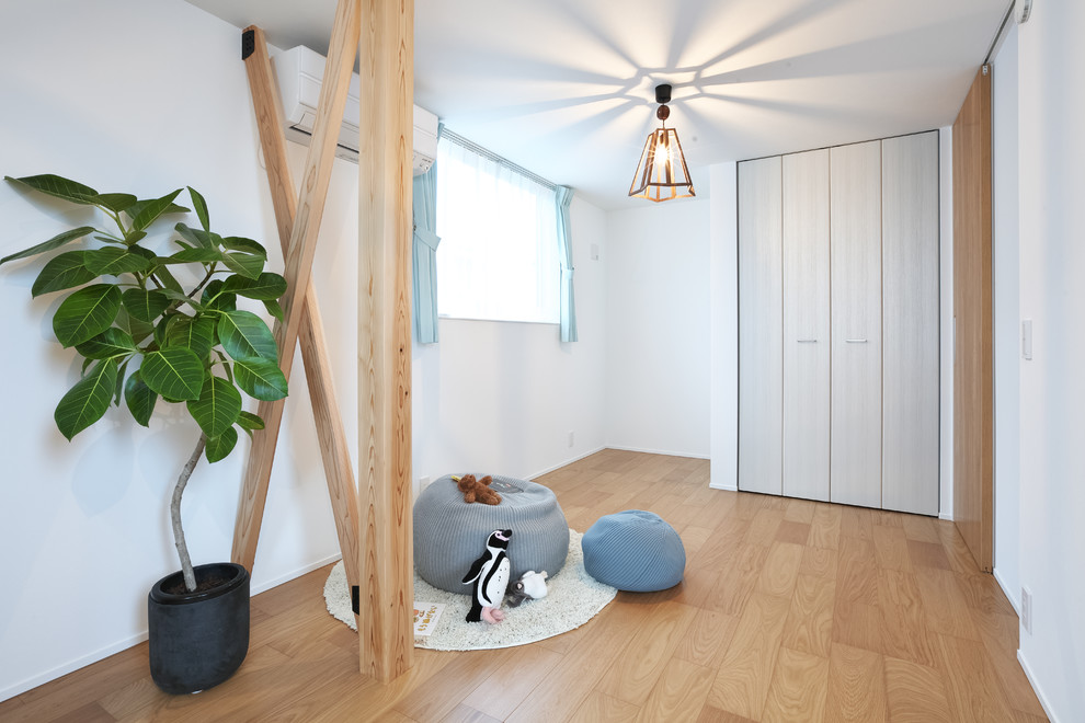 This is an example of a large modern gender-neutral kids' room in Other with white walls, medium hardwood floors and beige floor.