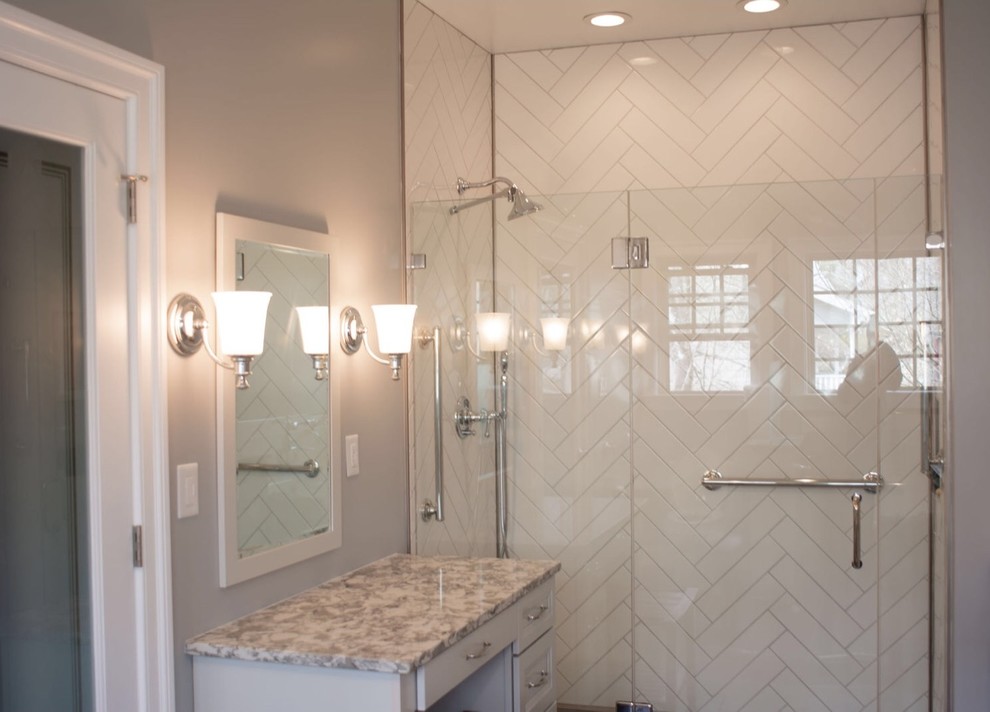 Photo of a large transitional master bathroom in Other with recessed-panel cabinets, grey cabinets, a freestanding tub, an alcove shower, white tile, subway tile, grey walls, porcelain floors, granite benchtops, grey floor, a hinged shower door and multi-coloured benchtops.