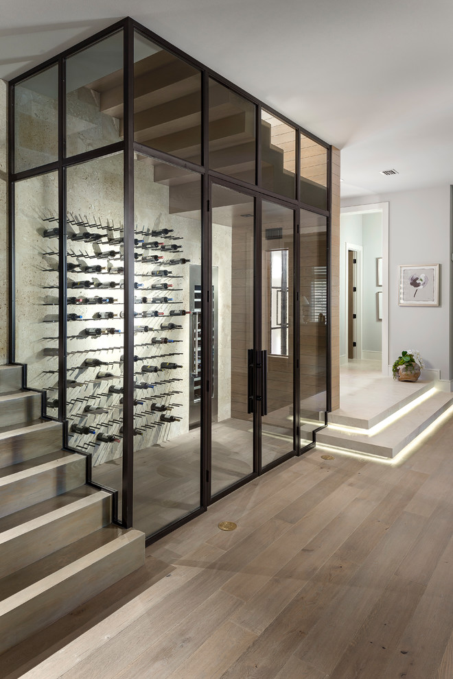 Contemporary wine cellar in Orlando with light hardwood floors and storage racks.