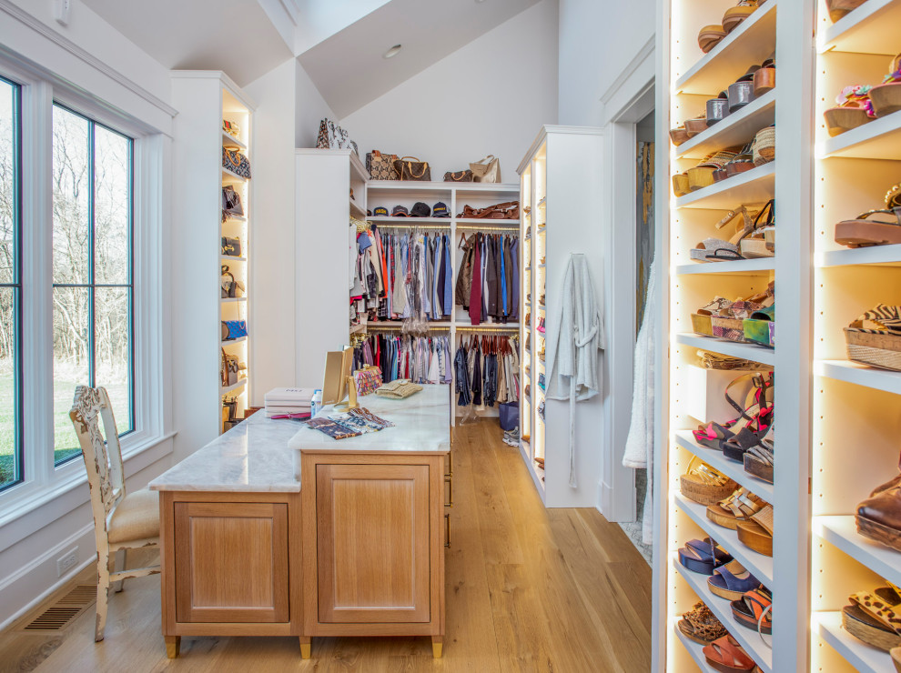 Inspiration for a large country gender-neutral walk-in wardrobe in Nashville with beaded inset cabinets, light wood cabinets, light hardwood floors, brown floor and vaulted.