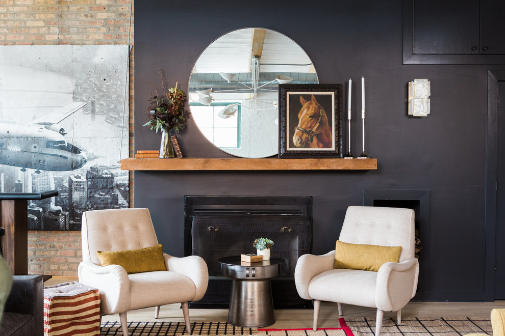 Photo of an industrial loft-style living room in Chicago with black walls, light hardwood floors and a standard fireplace.