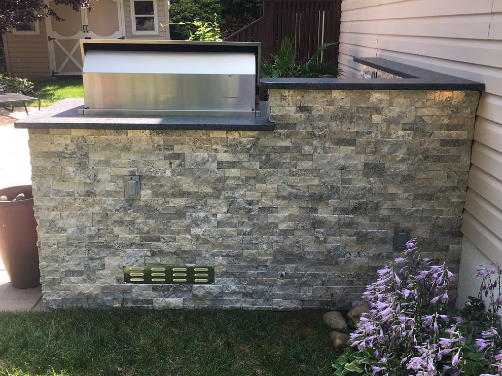 This is an example of a mid-sized transitional side yard patio in New York with an outdoor kitchen, natural stone pavers and no cover.