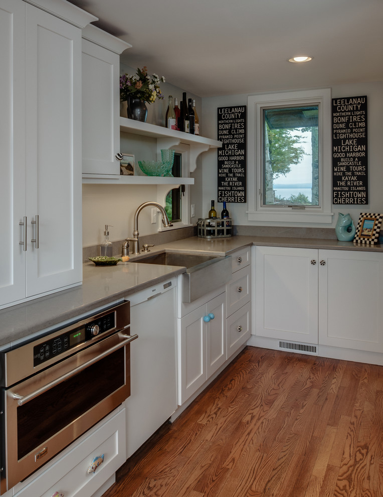 This is an example of an eclectic eat-in kitchen in Other with a farmhouse sink, recessed-panel cabinets, white cabinets, marble benchtops, white splashback, subway tile splashback and stainless steel appliances.