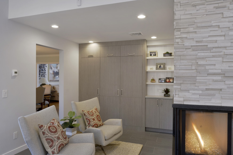 This is an example of a small modern living room in New York with limestone floors, white walls, a hanging fireplace and a stone fireplace surround.