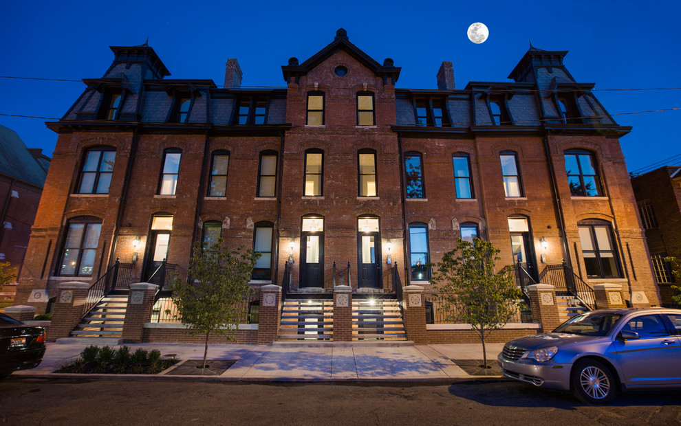 Example of a mid-sized ornate red three-story brick apartment exterior design with a tile roof