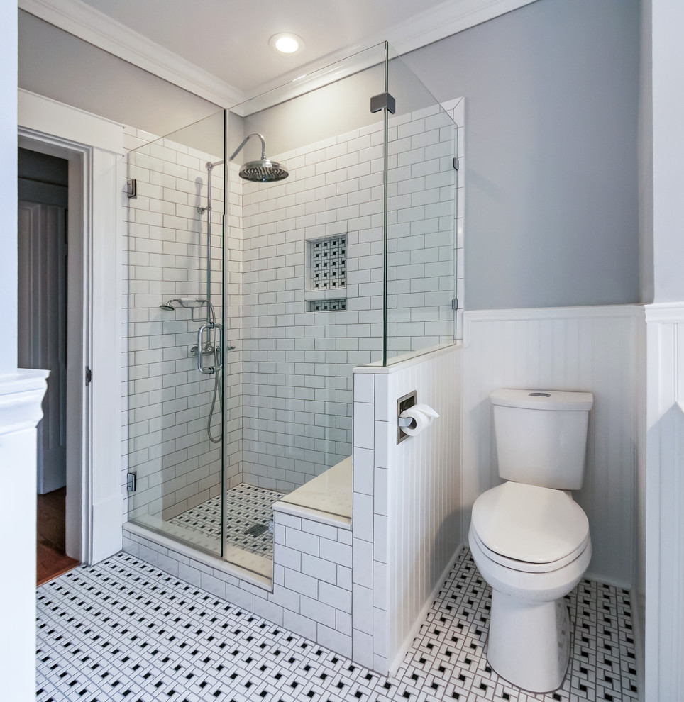This is an example of a mid-sized traditional 3/4 bathroom in Houston with a two-piece toilet, grey walls, multi-coloured floor, black cabinets, a claw-foot tub, a corner shower, white tile, subway tile, ceramic floors, an undermount sink, solid surface benchtops and a hinged shower door.