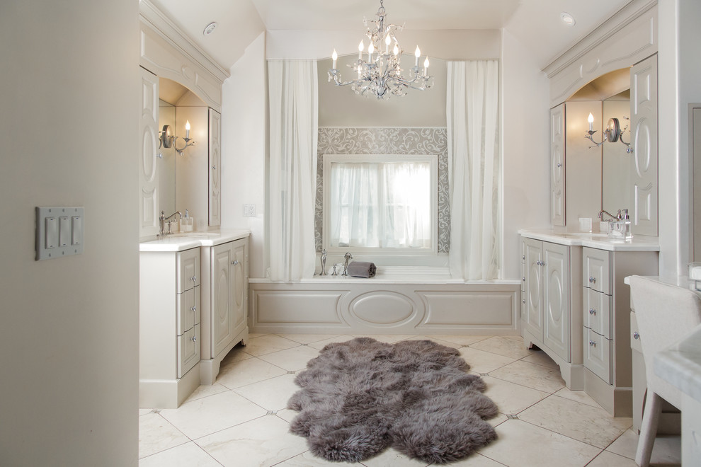 Photo of an expansive transitional master bathroom in Other with furniture-like cabinets, beige cabinets, an alcove tub, an alcove shower, a two-piece toilet, gray tile, stone slab, beige walls, limestone floors, an undermount sink, limestone benchtops, beige floor and a hinged shower door.