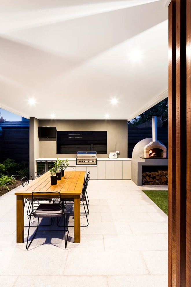 This is an example of a mid-sized contemporary backyard patio in Melbourne with an outdoor kitchen, natural stone pavers and a pergola.
