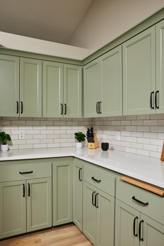 Example of a mid-sized transitional u-shaped vinyl floor and brown floor eat-in kitchen design in Minneapolis with an undermount sink, shaker cabinets, green cabinets, quartz countertops, white backsplash, ceramic backsplash, stainless steel appliances, an island and white countertops