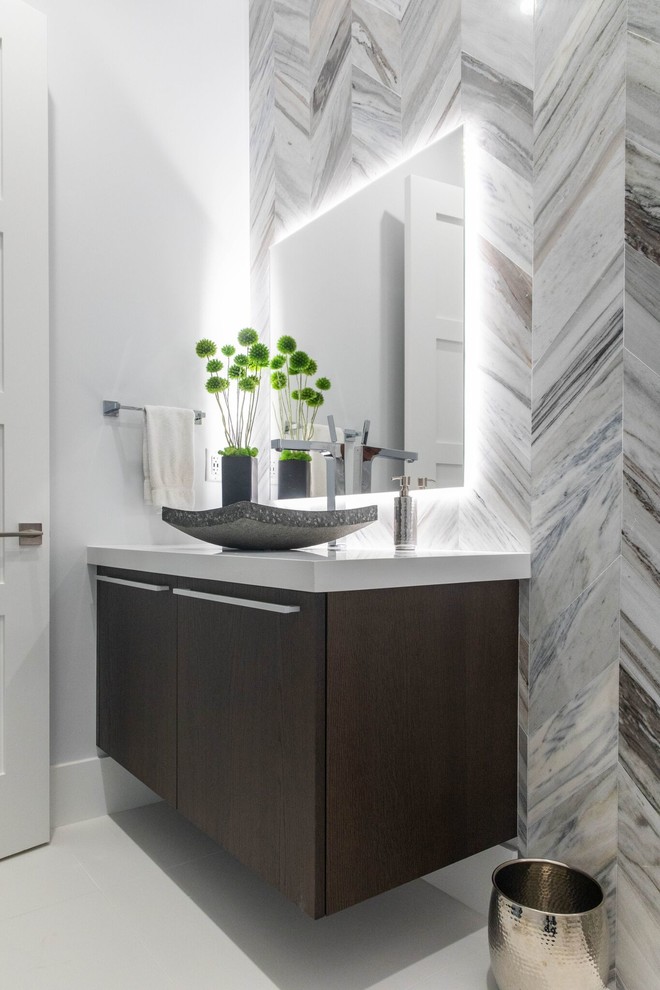 Design ideas for a mid-sized contemporary powder room in Miami with flat-panel cabinets, dark wood cabinets, a one-piece toilet, gray tile, marble, blue walls, porcelain floors, a vessel sink, engineered quartz benchtops, white floor and white benchtops.