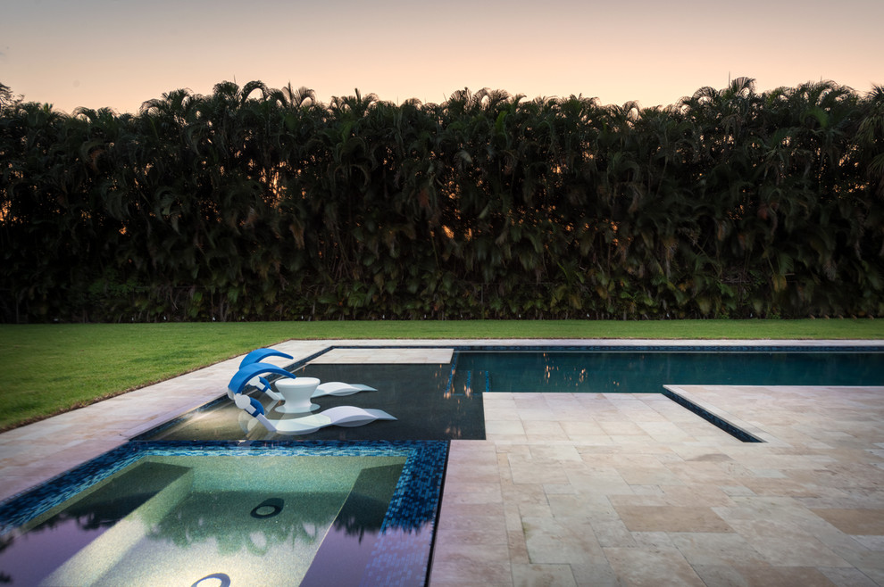 Design ideas for a large modern backyard l-shaped lap pool in Miami with a hot tub and natural stone pavers.