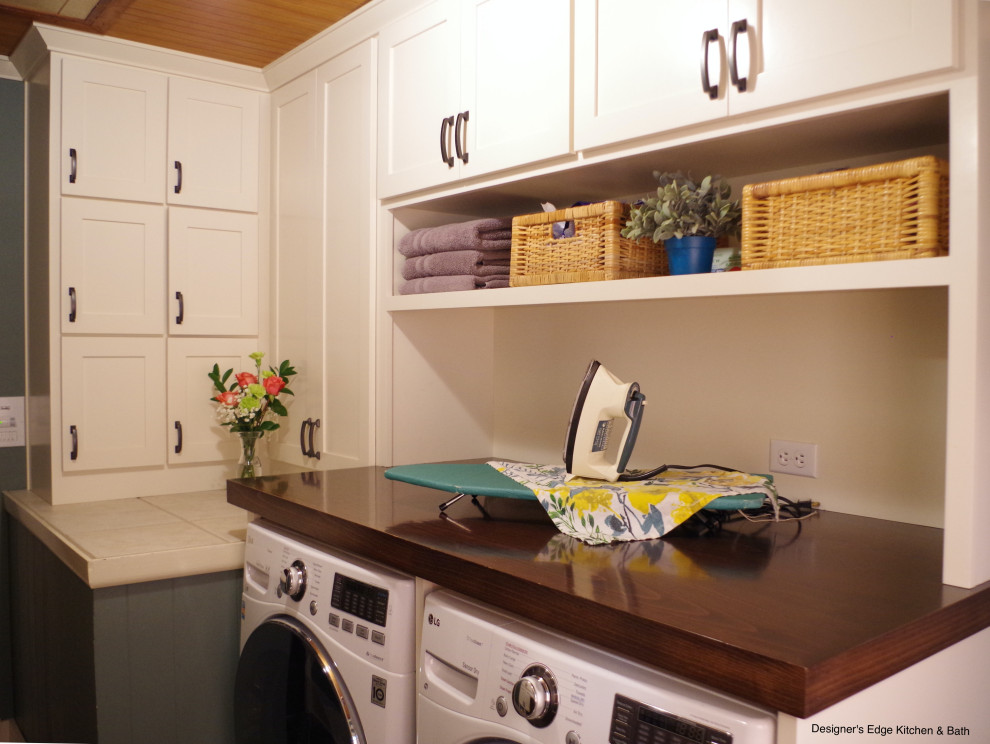 This is an example of a small arts and crafts single-wall utility room in Portland with a single-bowl sink, shaker cabinets, white cabinets, wood benchtops, green walls, slate floors, a side-by-side washer and dryer, brown benchtop and wood.