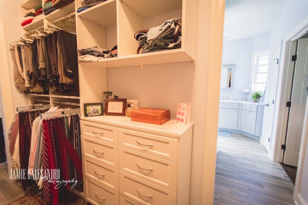 Photo of a mid-sized transitional gender-neutral walk-in wardrobe in Cleveland with shaker cabinets, white cabinets and light hardwood floors.