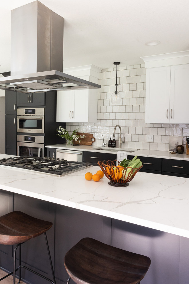 Mid-sized transitional galley vinyl floor and brown floor eat-in kitchen photo with an undermount sink, shaker cabinets, black cabinets, quartz countertops, white backsplash, stainless steel appliances, an island and white countertops