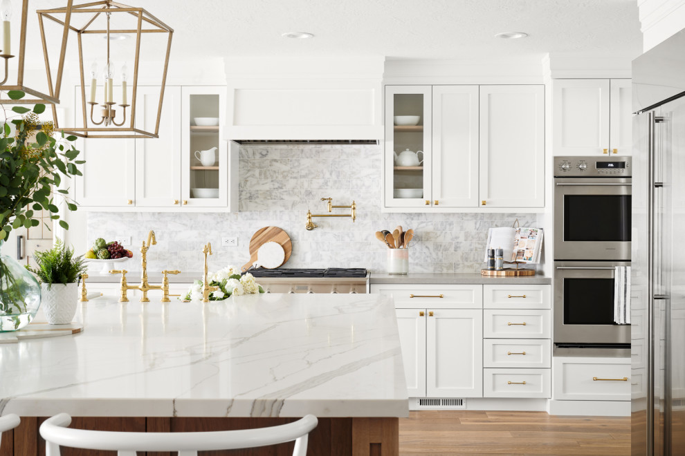 Large scandinavian l-shaped kitchen in San Francisco with a farmhouse sink, white cabinets, white splashback, stainless steel appliances, with island, recessed-panel cabinets, quartzite benchtops, marble splashback, light hardwood floors, beige floor and white benchtop.