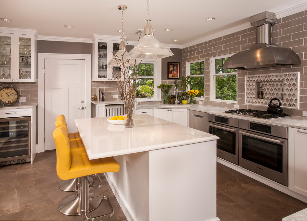 Large transitional l-shaped kitchen in Seattle with white cabinets, grey splashback, subway tile splashback, stainless steel appliances, with island, brown floor, white benchtop, an undermount sink and shaker cabinets.