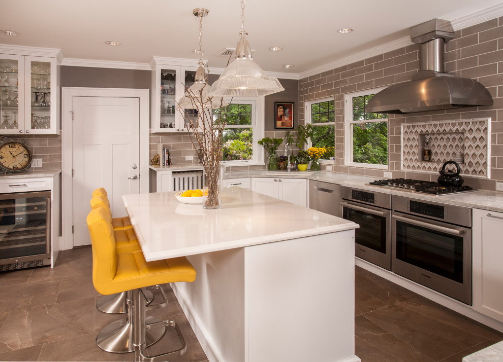 Inspiration for a large transitional l-shaped brown floor kitchen remodel in Seattle with white cabinets, gray backsplash, subway tile backsplash, stainless steel appliances, an island, white countertops, an undermount sink and shaker cabinets