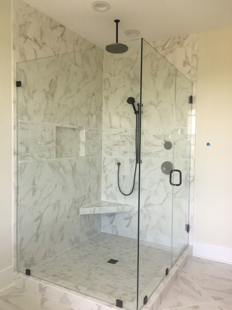 This is an example of a large contemporary master bathroom in Charleston with a corner shower, gray tile, white tile, marble, beige walls, marble floors, white floor and a hinged shower door.