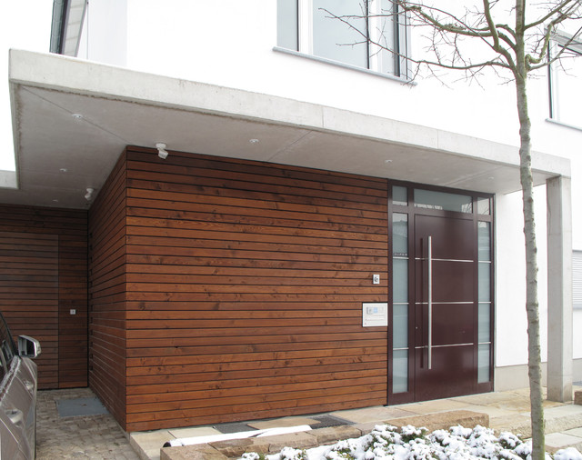 Eingangsbereich mit Holzfassade und Vordach aus Sichtbeton - Modern