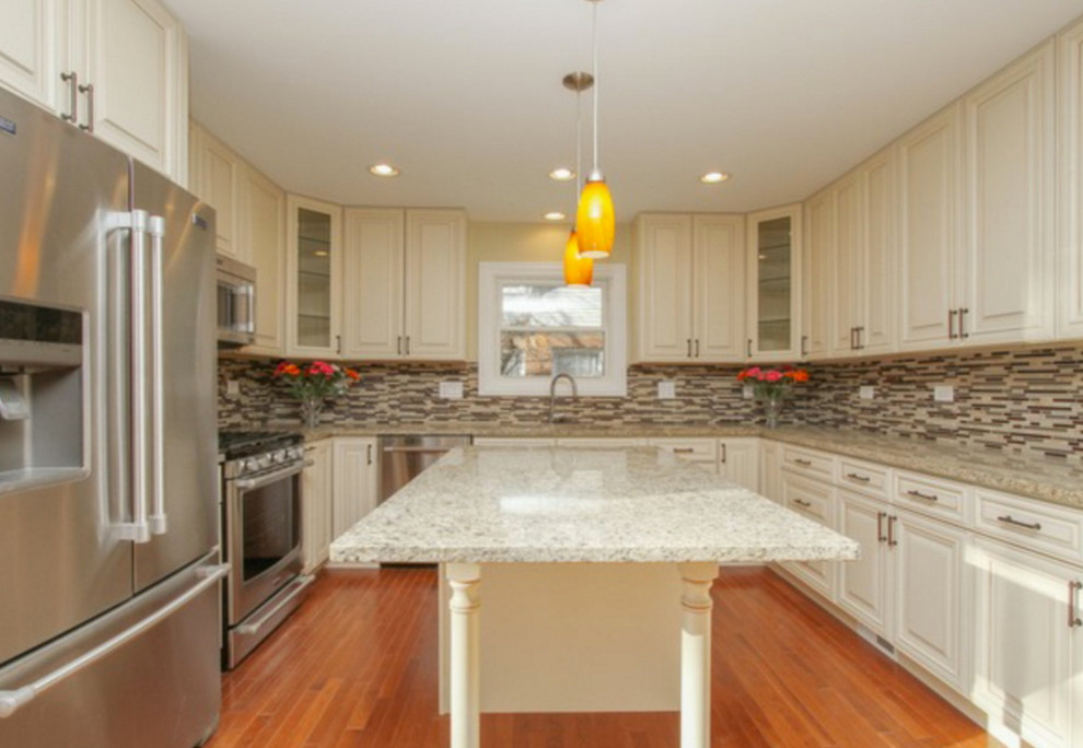 Open concept kitchen - mid-sized transitional u-shaped medium tone wood floor open concept kitchen idea in Chicago with an undermount sink, raised-panel cabinets, white cabinets, granite countertops, multicolored backsplash, matchstick tile backsplash, stainless steel appliances and an island