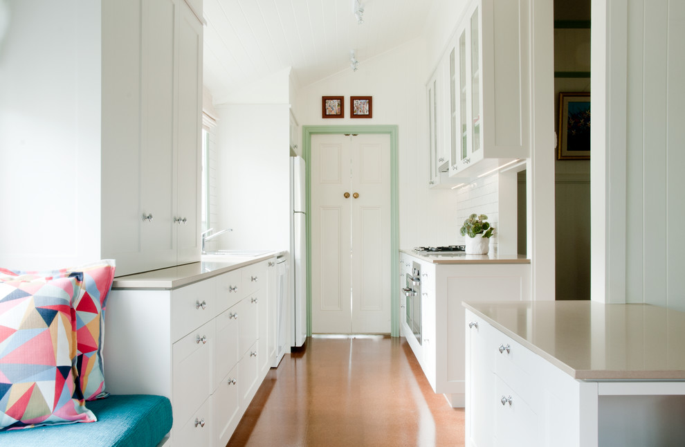Photo of a small traditional galley kitchen in Brisbane with white cabinets and white appliances.