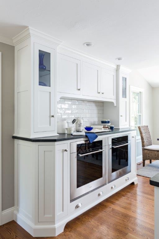 Example of a large beach style l-shaped medium tone wood floor open concept kitchen design in Boston with an undermount sink, recessed-panel cabinets, white cabinets, granite countertops, white backsplash, ceramic backsplash, stainless steel appliances and an island