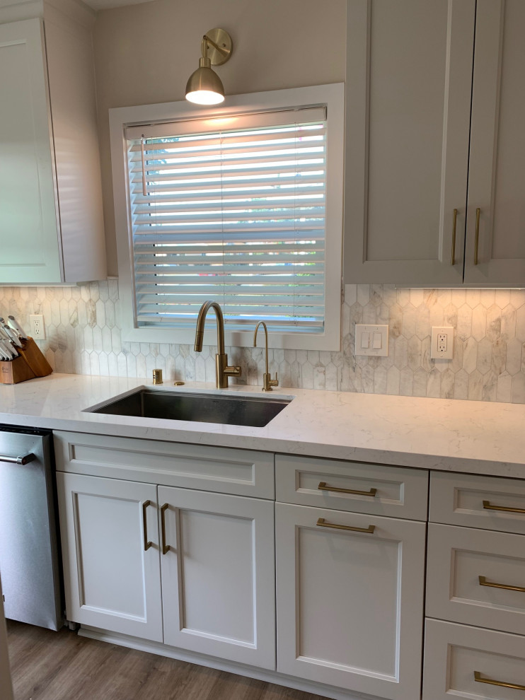Photo of a medium sized contemporary l-shaped kitchen/diner in Los Angeles with a built-in sink, flat-panel cabinets, white cabinets, quartz worktops, white splashback, porcelain splashback, stainless steel appliances, vinyl flooring, an island, beige floors and white worktops.