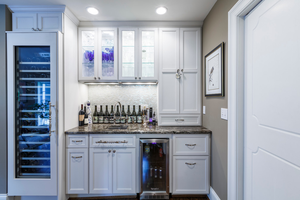 Small traditional single-wall wet bar in Cincinnati with an undermount sink, recessed-panel cabinets, white cabinets, white splashback and mosaic tile splashback.