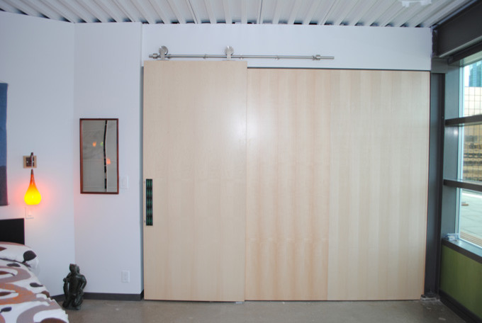 Foto di un armadio o armadio a muro unisex contemporaneo di medie dimensioni con ante lisce, ante in legno chiaro, pavimento in cemento e pavimento grigio
