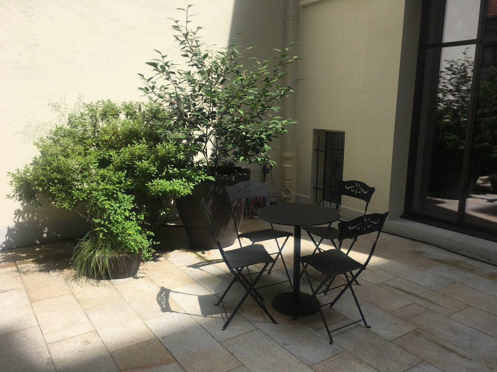 Small traditional courtyard patio in Other with a vegetable garden and natural stone pavers.
